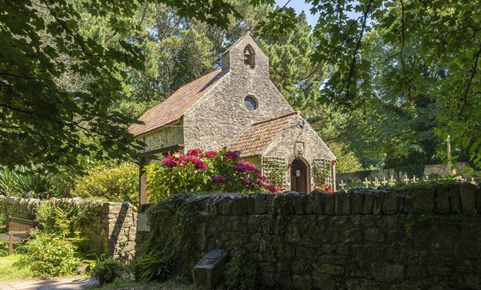 Historic St David's Church on Caldey Island set among mature trees and landscaped gardens.